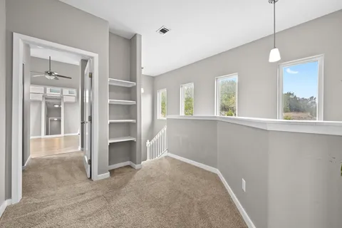 a view of an empty room with a window and a kitchen