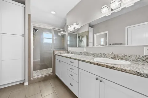 a bathroom with a granite countertop sink a mirror and a shower