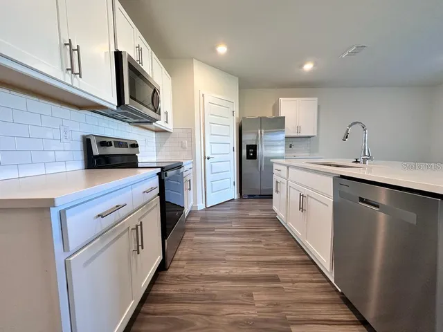 a kitchen with stainless steel appliances a sink stove microwave and cabinets