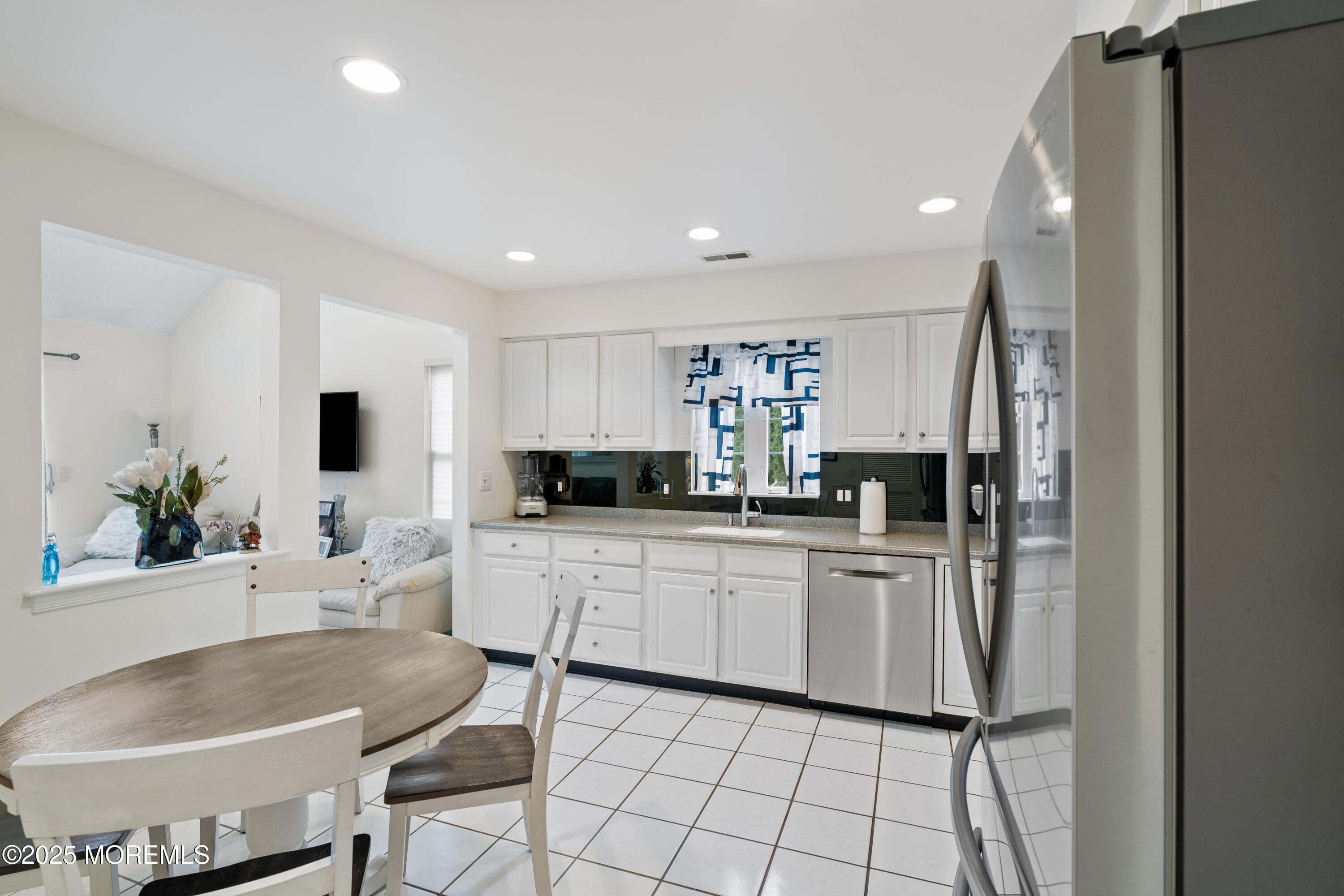 7 Regent Square Jackson, NJ 08527 - Photo 4 of 29 a kitchen with white cabinets a sink dining table and chairs