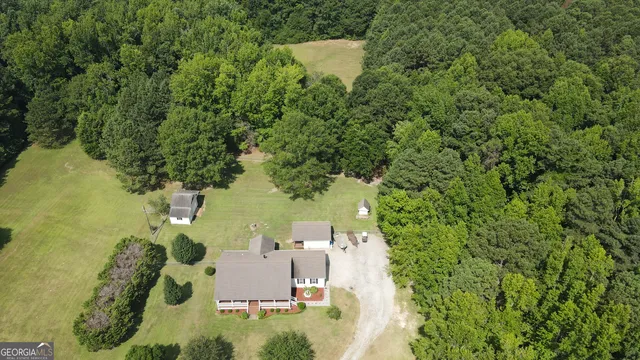 an aerial view of residential house with outdoor space and trees all around