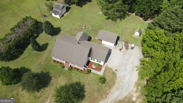 an aerial view of residential house with outdoor space and trees all around