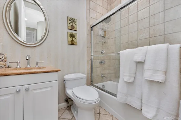 a bathroom with a toilet sink vanity granite and shower