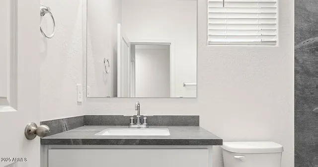 a bathroom with a granite countertop sink and a toilet