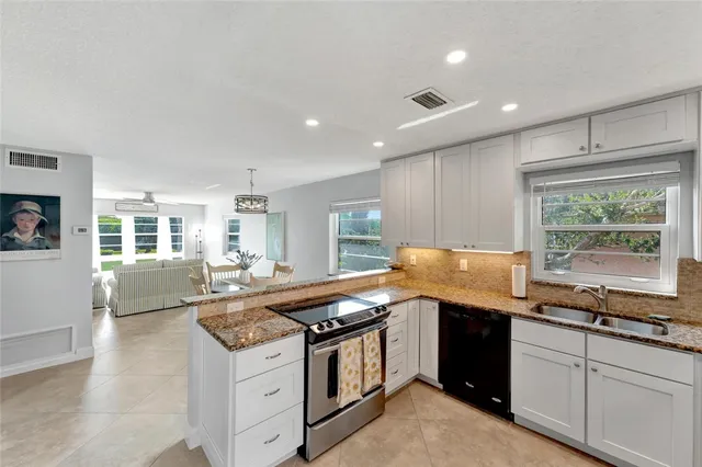 a kitchen with granite countertop stainless steel appliances a sink stove and cabinets