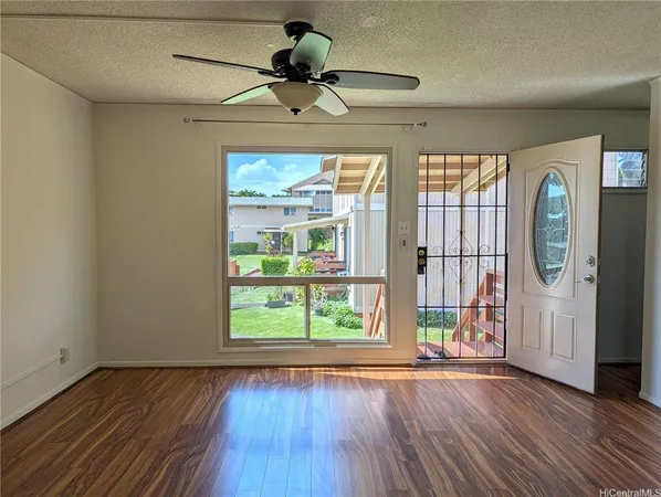 a view of an empty room with a window and wooden floor