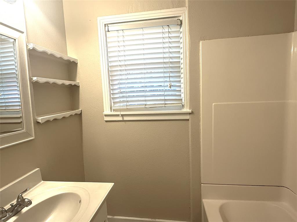 4718 Normandy Road Fort Worth, TX 76103 - Photo 11 of 26 Bathroom featuring a built-in vanity with an integrated sink, polished chrome faucet, a rectangular mirror, and three decorative wall shelves