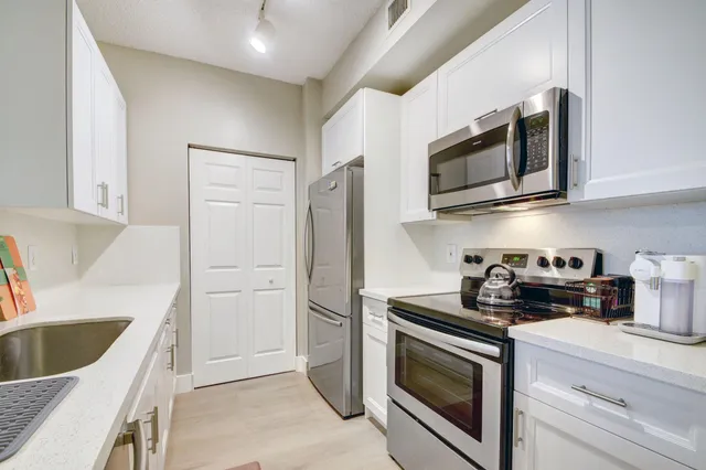 a kitchen with stainless steel appliances granite countertop white cabinets a stove a microwave and a refrigerator