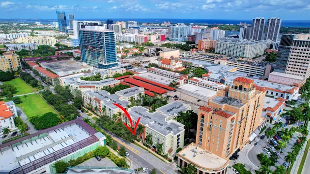 a front view of a residential apartment building with a yard and palm trees