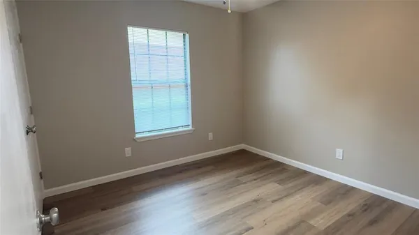 an empty room with wooden floor cabinet and windows