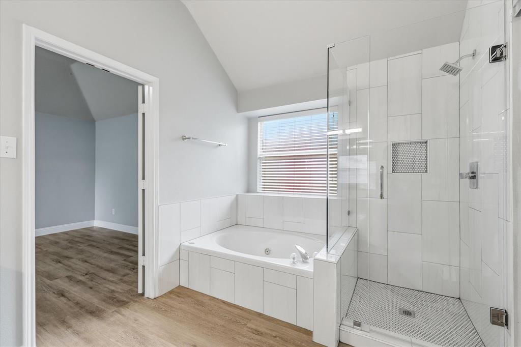 2616 Hollow Ridge Drive Denton, TX 76210 - Photo 22 of 31 Full bathroom featuring a built-in jetted tub, a separate glass-enclosed shower with a rain shower head, white tiled walls, and wood-finish flooring