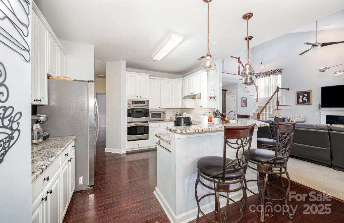 6930 Reedy Creek Road Charlotte, NC 28215 - Photo 27 of 28 a kitchen with stainless steel appliances kitchen island granite countertop a table chairs refrigerator and microwave
