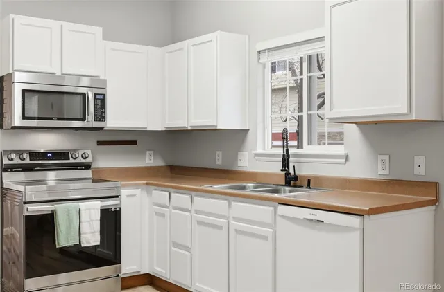 a kitchen with granite countertop white cabinets stainless steel appliances and a sink