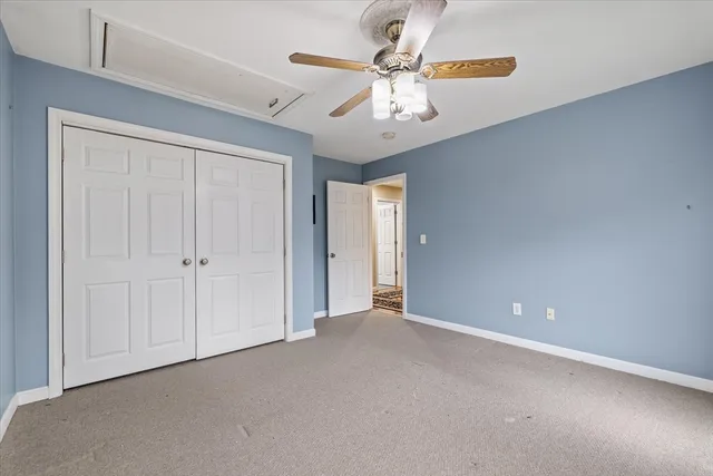 an empty room with a chandelier fan and windows
