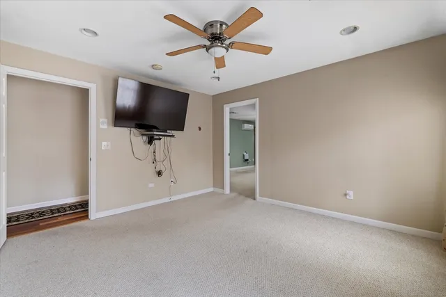 an empty room with windows flat screen tv and a ceiling fan