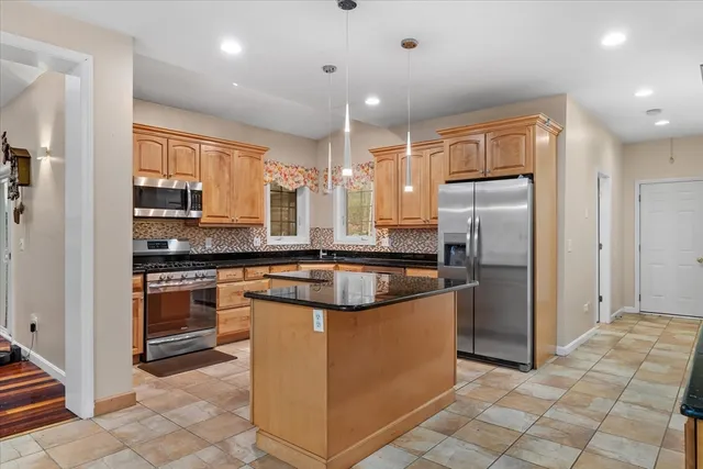 a kitchen with stainless steel appliances granite countertop a refrigerator a stove a sink and a microwave