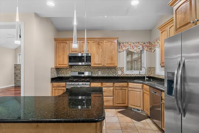 a kitchen with stainless steel appliances granite countertop a sink a stove and a refrigerator
