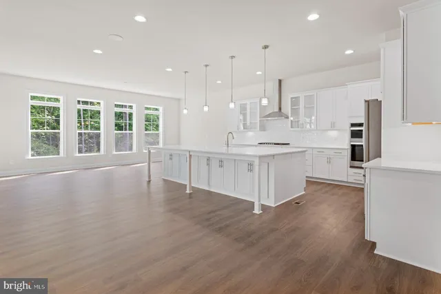 a large kitchen with stainless steel appliances kitchen island a large counter top and a wooden floors