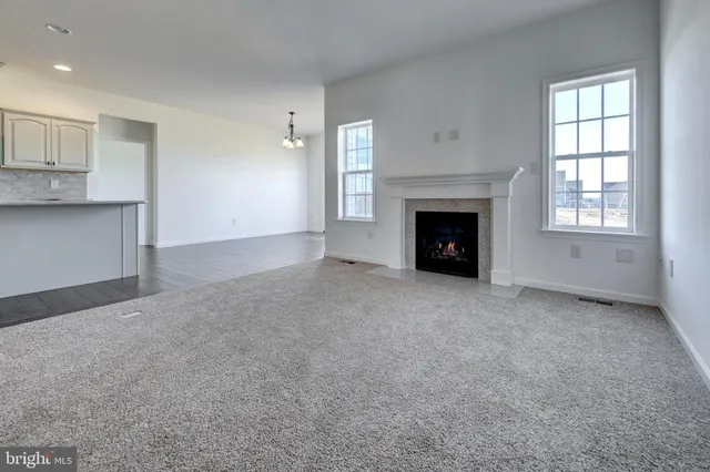 an empty room with windows and fireplace