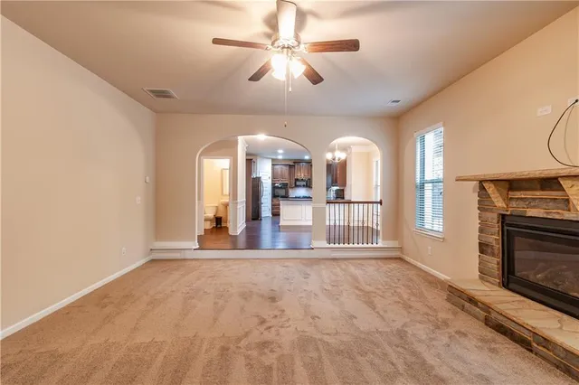 an empty room with a chandelier fan and windows