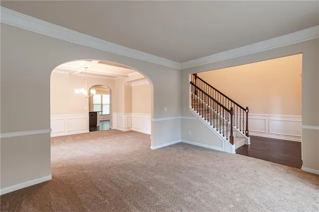 a view of an empty room with a window and kitchen view