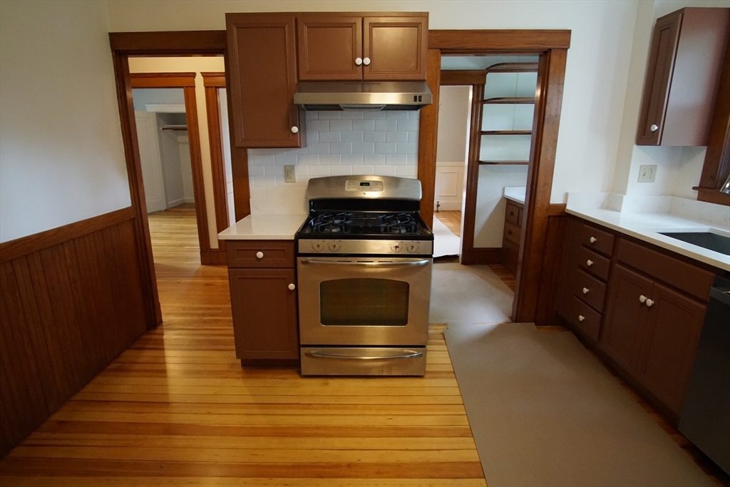 754 Massachusetts Avenue, Unit 1 Lexington, MA 02421 - Photo 11 of 17 a kitchen with granite countertop a stove and a wooden floor