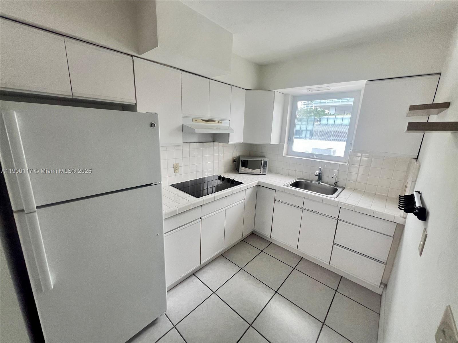158 Ocean Drive, Unit 406 Miami Beach, FL 33139 - Photo 5 of 9 a white refrigerator freezer sitting inside of a kitchen with white cabinets