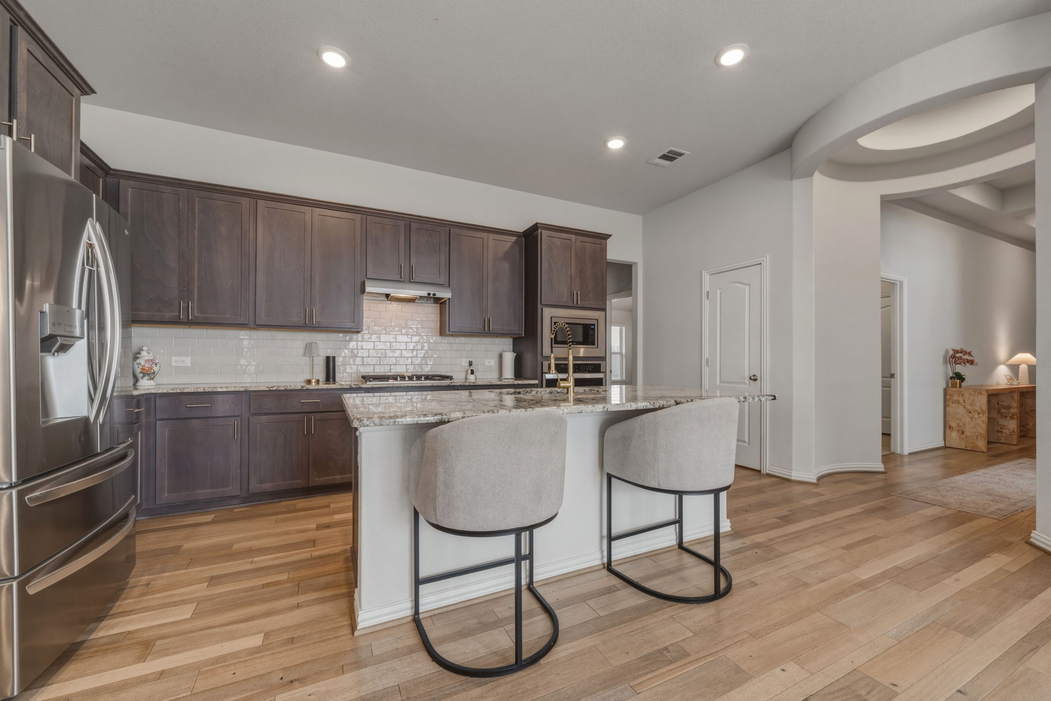 918 Leadtree Loop Buda, TX 78610 - Photo 7 of 27 Kitchen with stainless steel appliances, light stone countertops, a kitchen island with sink, dark wood finish cabinets, and a breakfast bar area