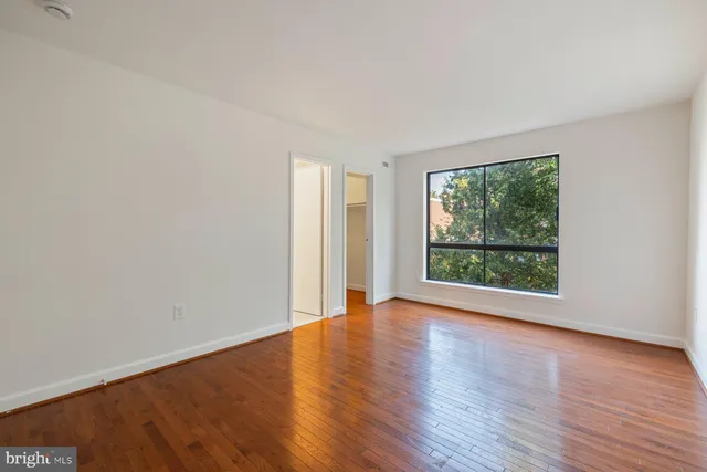 a view of an empty room with wooden floor and a window