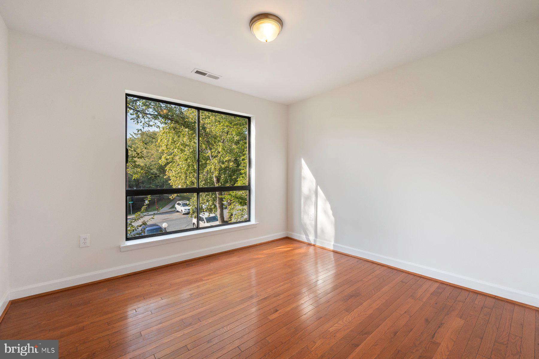 3946 Bel Pre Road, Unit 39466 Silver Spring, MD 20906 - Photo 6 of 27 an empty room with wooden floor and windows