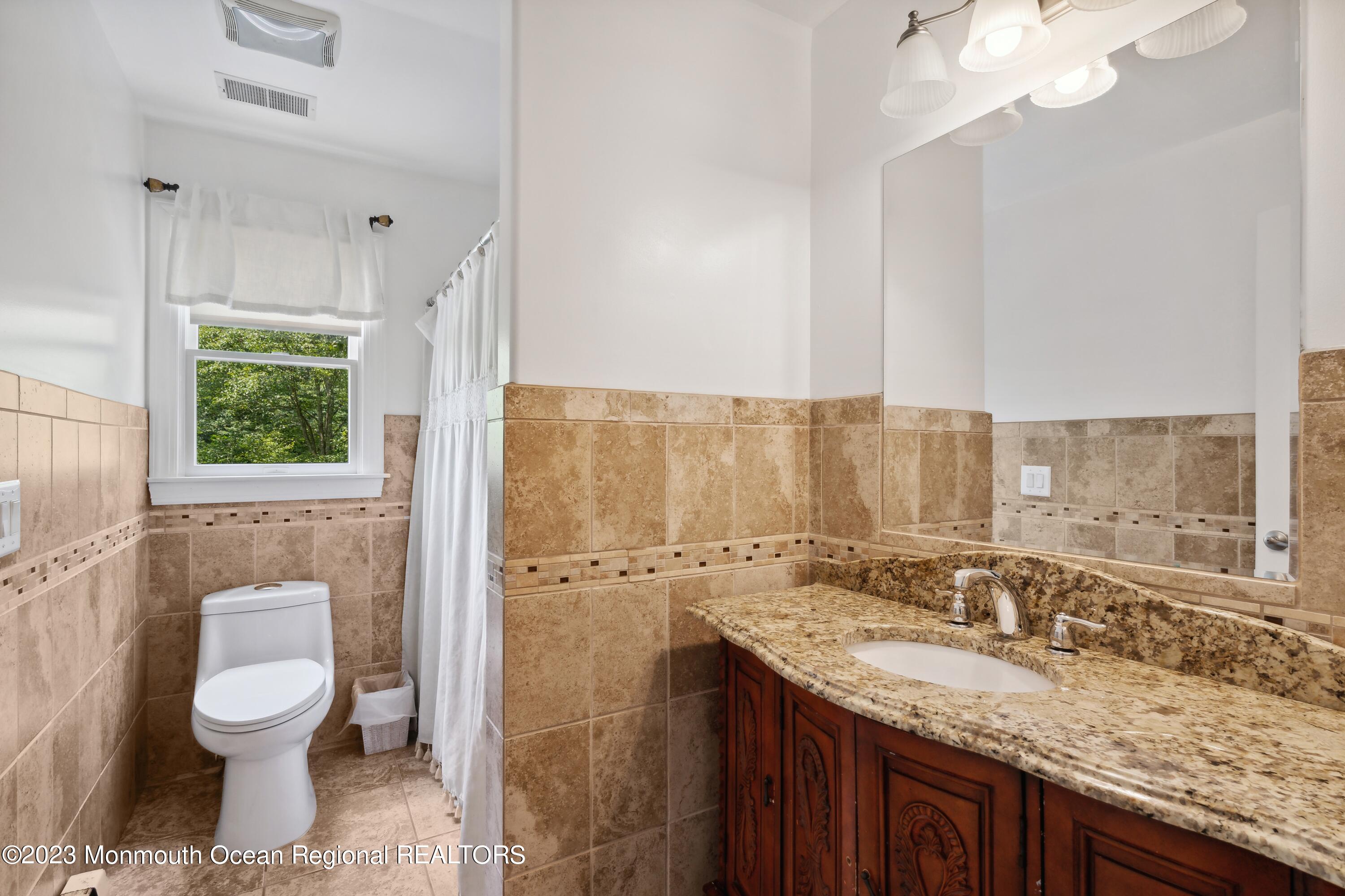 a bathroom with a granite countertop sink a toilet and a mirror