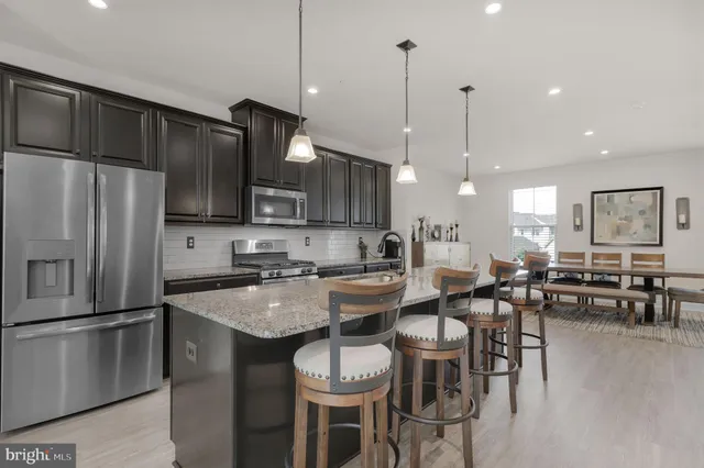 a kitchen with granite countertop a table chairs stove and refrigerator