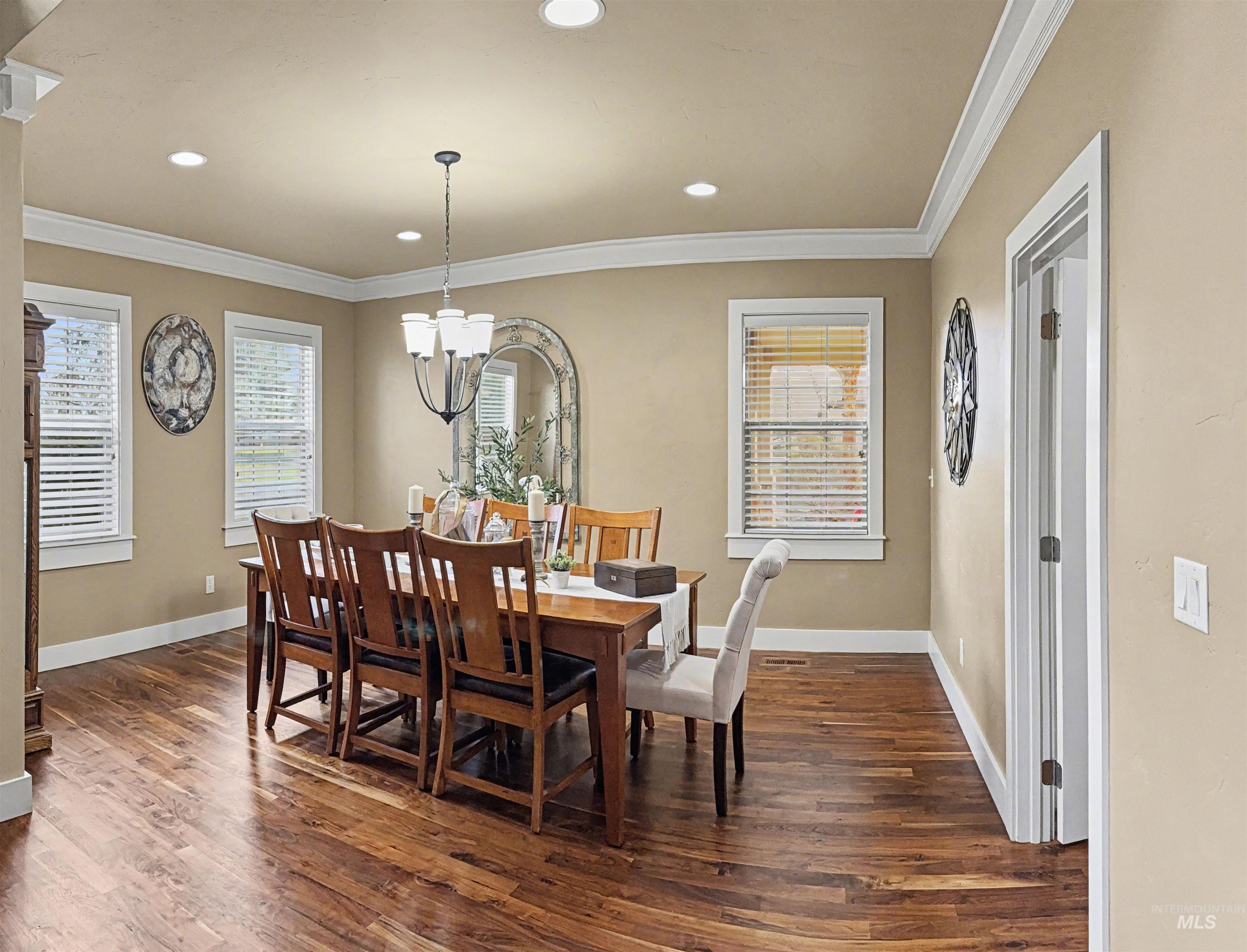 2425 South Chipper Way Eagle, ID 83616 - Photo 14 of 43 Dining room featuring dark wood-style floors, crown molding, healthy amount of natural light, a chandelier, and recessed lighting