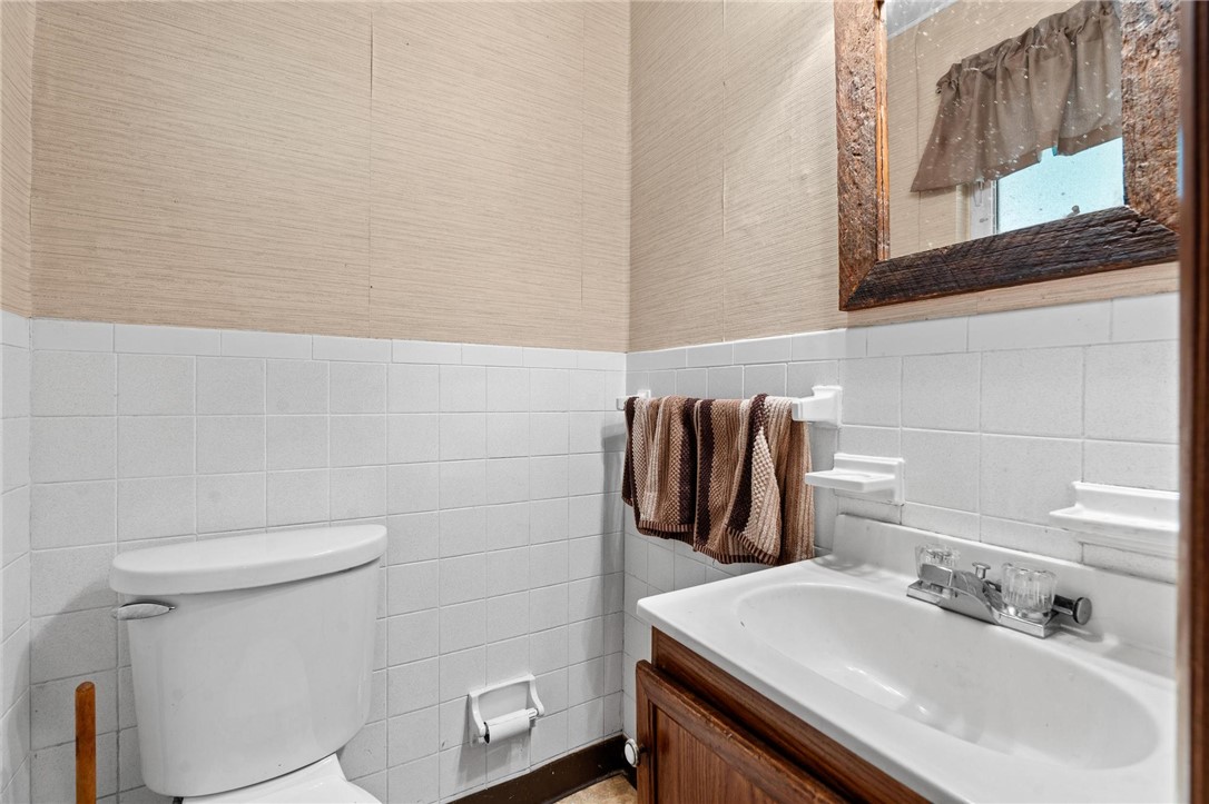4150 Rose Marie Road Franklin, OH 45005 - Photo 34 of 36 A well-maintained half-bath features classic tiled walls and a functional vanity with a simple sink.