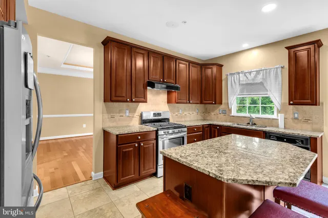 a kitchen with kitchen island granite countertop wooden cabinets a refrigerator and a sink