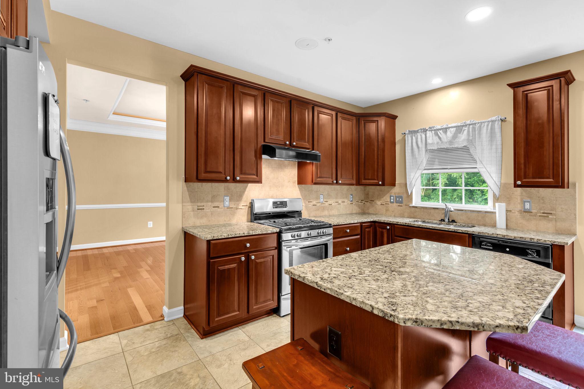 906 Gladway Road Baltimore, MD 21220 - Photo 7 of 52 a kitchen with kitchen island granite countertop wooden cabinets a refrigerator and a sink