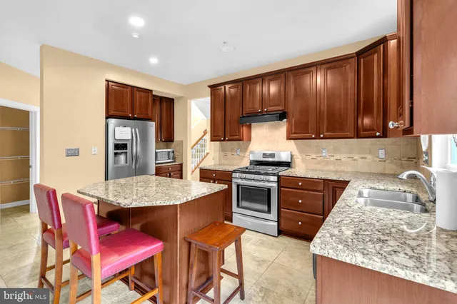 a kitchen with stainless steel appliances granite countertop a stove a refrigerator a sink a dining table and chairs