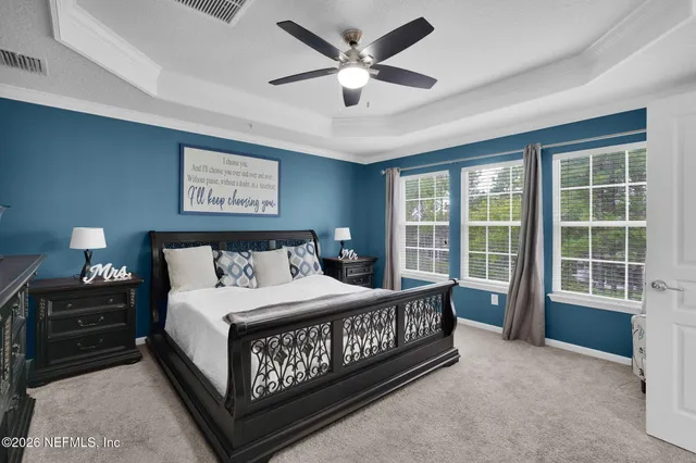 a bedroom with a bed painting on wall and a large window