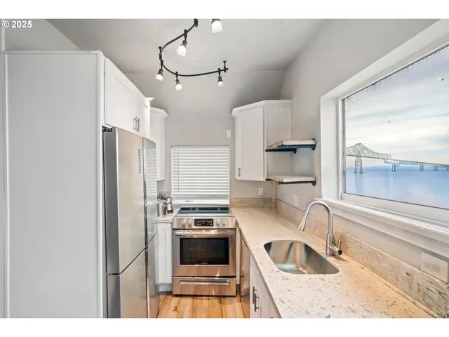 a kitchen with stainless steel appliances a sink a stove and a refrigerator with wooden floor