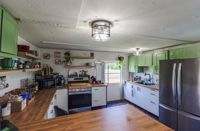 835 County Road 182 Marlin, TX 76661 - Photo 11 of 27 a kitchen with stainless steel appliances granite countertop a refrigerator a stove top oven a sink dishwasher and white cabinets with wooden floor