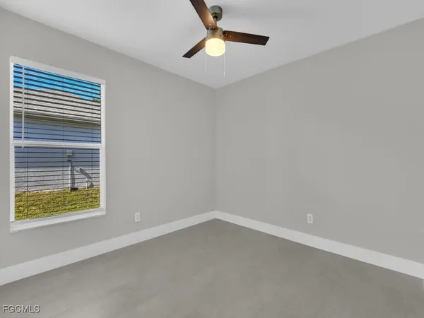an empty room with a window and ceiling fan