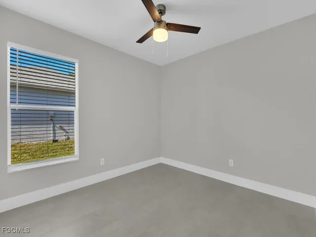 an empty room with a window and ceiling fan