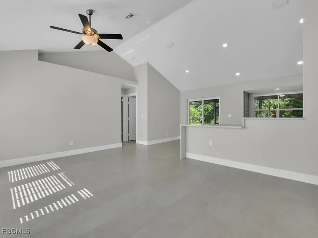 an empty room with a ceiling fan and windows