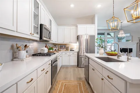 a kitchen with granite countertop stainless steel appliances a sink a stove and cabinets