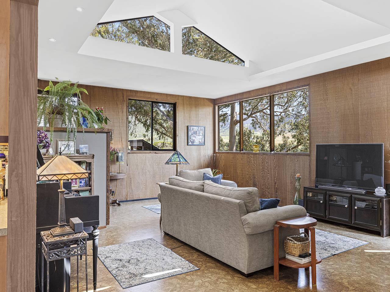 3405 Rio Road Carmel, CA 93923 - Photo 11 of 40 a living room with furniture a flat screen tv and a floor to ceiling window