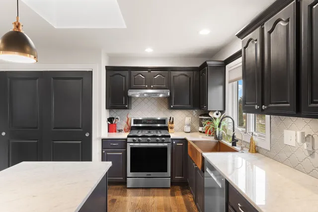 a kitchen with stainless steel appliances a stove a sink a refrigerator and chairs