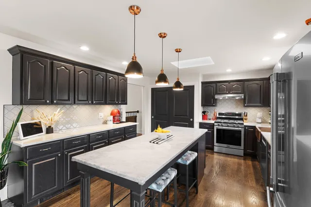 a kitchen with stainless steel appliances a stove a refrigerator a sink a oven with wooden floor and cabinets