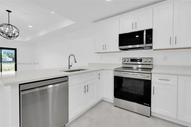 a kitchen with stainless steel appliances a stove microwave and sink