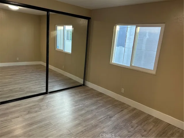 an empty room with wooden floor and mirror