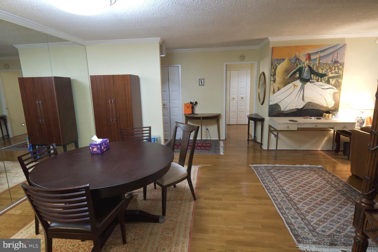 1800 Old Meadow Road, Unit 818 McLean, VA 22102 - Photo 14 of 35 a living room with furniture a dining table and paintings on the wall